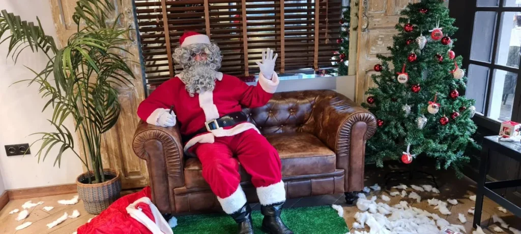 Papá Noel en sillón junto al árbol de Navidad, evento en Valencia
